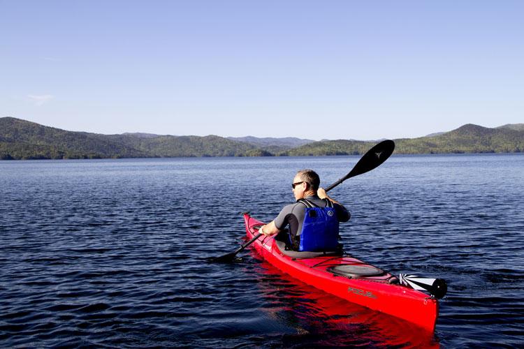 Man paddling a red kayak on the lake